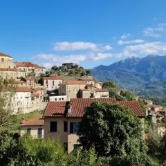 Panoramica di Mulazzo, borgo ligure con case in pietra e tetti rossi, dominato da un castello e con montagne sullo sfondo. Cosa vedere in questo incantevole paese.