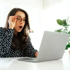 Zaskoczona kobieta odkrywa, ile dni urlopu można przenieść na następny rok, patrząc na ekran laptopa.