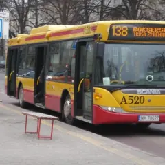 Żółto-czerwony autobus 138 warszawa z otwartymi drzwiami na przystanku.