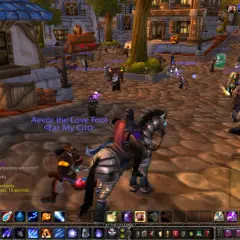 Gracz na koniu w świecie Warcraft, otoczony innymi postaciami i budynkami.