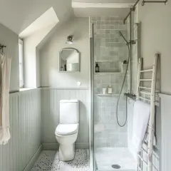 Douche, WC et lavabo dans une petite salle de bain 3m2. Un style épuré et fonctionnel avec des carreaux gris et un mur lambrissé.