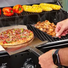 Na ruszcie grilla piecze się pyszna pizza z grilla, obok kurczak i kukurydza.