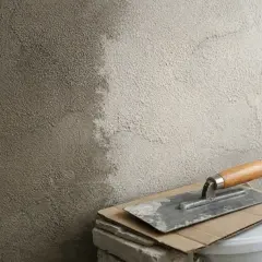 Narzędzia budowlane i świeżo nałożony tynk na ścianie. Czekamy, aż beton wyschnie, by kontynuować prace.