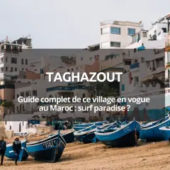 Village de pêcheurs à Taghazout, Maroc. Bateaux bleus sur la plage, maisons blanches perchées. Un paradis pour le surf au Maroc.