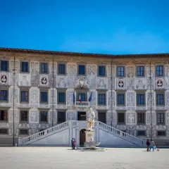 Piazza dei Cavalieri a Pisa: un palazzo storico con affreschi, una statua e una fontana. Cosa vedere a Pisa? Questo è un must!