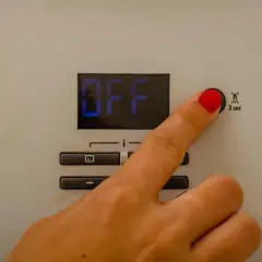 Dito che preme il pulsante per il reset caldaia Immergas. Lo schermo mostra "OFF".