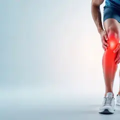 Mężczyzna trzymający się za bolące kolano, z zaznaczonym na czerwono obszarem bólu.