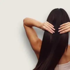 En kvinna med långt, mörkt hår som glänser av keratin protein. Håret är slätt och friskt.