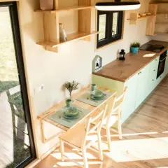 Gemütliches tiny house innen mit Esstisch, Küche und Blick ins Grüne.