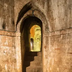 Un antico passaggio conduce ai **Bologna canali sotterranei**. Scale di pietra scendono nell'oscurità, tra muri di mattoni e archi in mattoni.