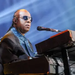 Niewidomy piosenkarz Stevie Wonder gra na keyboardzie Yamaha podczas koncertu.