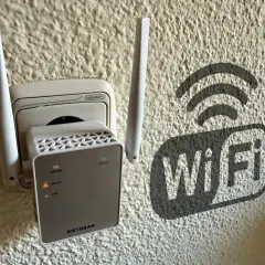 Extensor de red **wireless WAN** enchufado a la pared, con un símbolo de Wi-Fi al lado.