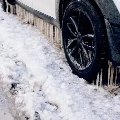 Lodowe sople zwisają z progu samochodu, który utknął w śniegu. Diesel potrzebuje samostartu, by ruszyć.