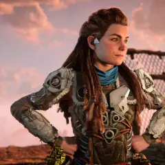 Aloy z Horizon Forbidden West, w zbroi z metalowymi płytami, patrzy w dal na tle zachodzącego słońca.