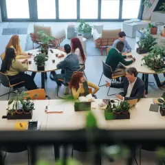 Ludzie pracują i rozmawiają w jasnej przestrzeni, która pokazuje, coworking co to.