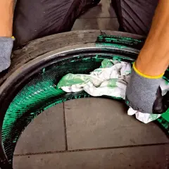 Ręce w rękawiczkach czyszczą wnętrze opony z zielonej substancji. Czy opona po zestawie naprawczym jest do wyrzucenia?