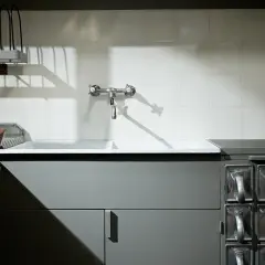 Stara kuchnia frankfurcka z ceramicznym zlewem, kranem i rzędem metalowych pojemników na przyprawy.
