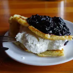 Puszyste naleśniki z bitą śmietaną i jagodami, idealne do menu chatki górzystów.