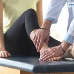 Fizjoterapeuta bada podkręconą kostkę pacjentki.
