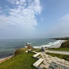 Un paseo en bicicleta por las **playas cerca de Foz**, con el mar Cantábrico de fondo y un cielo nublado.