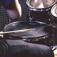 Pałeczka spoczywa na werblu, gotowa do uderzenia w ten duży instrument perkusyjny.