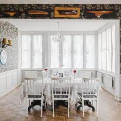 Elegant matsal med dukat bord, blommig tapet och modellbåtar i taket. Perfekt för en middag, som recensionerna för Villa Godthem antyder.