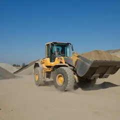 Żółta ładowarka Volvo z pełną łyżką ziemi. Posiadanie uprawnień na koparko ładowarki klasa 1 to klucz do obsługi takich maszyn.