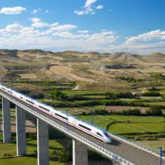 Schneller Zug auf einer Hochbahnbrücke, der die Landschaft von Deutschland nach Spanien durchquert.