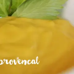Un bol de crémeux aioli provençal, garni d'une feuille verte fraîche.