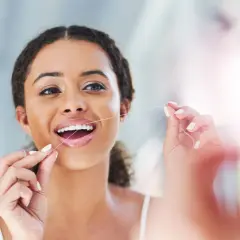 Donna sorridente usa il filo interdentale, un gesto quotidiano per un sorriso sano. Quante volte usare il filo interdentale? Almeno una volta al giorno.