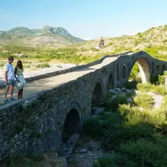 Pareja admira un puente de piedra histórico, un lugar perfecto para un viaje a Albania de 5 días.