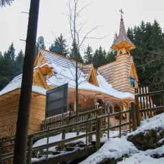 Drewniane sanktuarium maryjne na Wiktorówkach w zimowej scenerii, otoczone lasem iglastym.