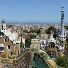 Widok na Park Güell w Barcelonie, z mozaikowymi budynkami i panoramą miasta. Ceny w Barcelonie mogą być wysokie, ale widoki są bezcenne.