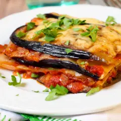 Deliciosa lasaña de berenjena, capas de berenjena, salsa de tomate y queso fundido, espolvoreada con perejil fresco.
