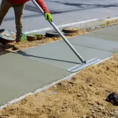 Robotnik wygładza świeży beton C25/30 na budowie chodnika.