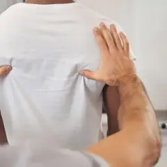 Fizjoterapeuta bada plecy pacjenta, szukając przyczyn objawów neurologicznych kręgosłupa piersiowego.