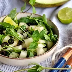 Refrescante ensalada de melón con rúcula, aceitunas negras y menta. Un toque de lima realza su sabor.