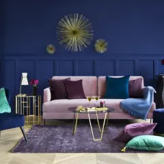 Elegancki salon z granatową ścianą, różową kanapą i złotymi dodatkami. Inspiracje dla odważnych.