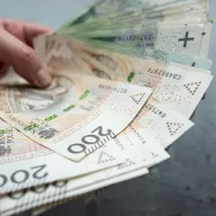 Dłoń trzyma plik banknotów 200 zł. Czy współwłaściciel konta może wypłacić pieniądze po śmierci właściciela?