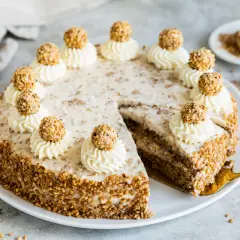 Eine köstliche Giotto Torte, verziert mit Sahnetuffs und Haselnusskugeln, umgeben von gehackten Nüssen.