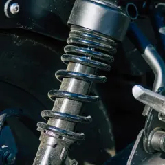 Sprężyna amortyzatora motocykla jest brudna i porysowana, co może wskazywać na uszkodzony amortyzator objawy.