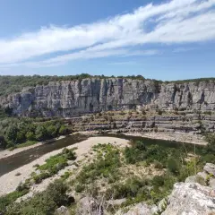 Un cirque de gens, des kayakistes profitent de la rivière au pied d'une falaise imposante.