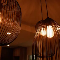 Trzy nowoczesne lampy wiszące z metalowymi kloszami i żarówkami Edisona.