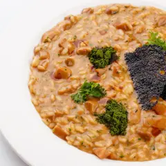 Risotto z grzybami i zieloną posypką na białym talerzu.