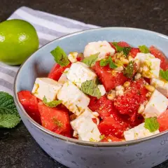 Erfrischender Wassermelone Feta Salat mit Minze und Pinienkernen, garniert mit Limettenabrieb. Ein leichter Genuss.