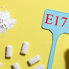 Biały proszek, tabletki i gumy do żucia. Tabliczka z napisem E171 sugeruje, że to właśnie dwutlenek tytanu, który często jest składnikiem tych produktów.