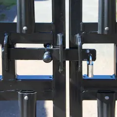Solidne zamknięcie bramy przesuwnej z kłódką. Metalowa konstrukcja zabezpiecza teren.