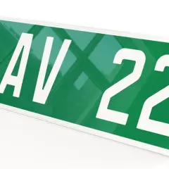 Plaque verte voiture avec "123 AV 22" en blanc. D'autres plaques similaires sont empilées en dessous.
