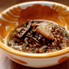 Un reconfortante plato de lentejas con boletus, servido en un cuenco decorado con motivos naranjas.