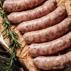 Surowa, świeża kiełbasa na desce, z gałązkami rozmarynu i papryczką chili. Zastanawiasz się, ile kiełbasa może być w zamrażarce?